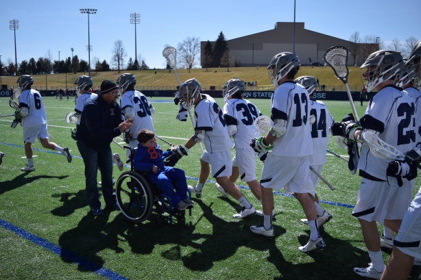 Gavin Royer high fives his Penn State teammates as they enter the field prior to their game against Ohio State. Royer was drafted by the Nittany Lions men's team along with his two sisters to the women's lacrosse team and attend as many games as the can. Photo by: Matt Custodio